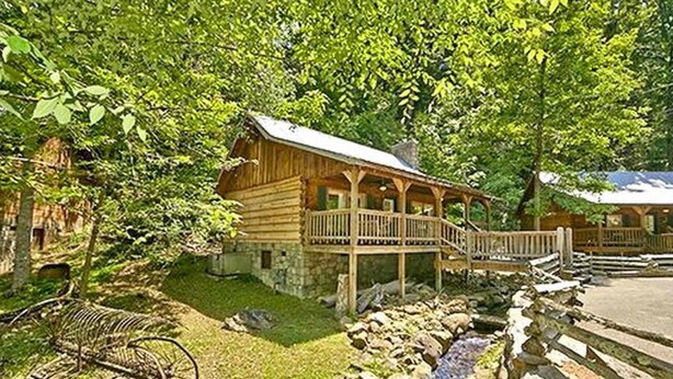Une cabane rustique en rondins de bois, dotée d’un porche et construite sur des fondations en pierre.