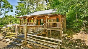 Un chalet rustique doté d’une terrasse en bois et d’un escalier en pierre menant à l’entrée.