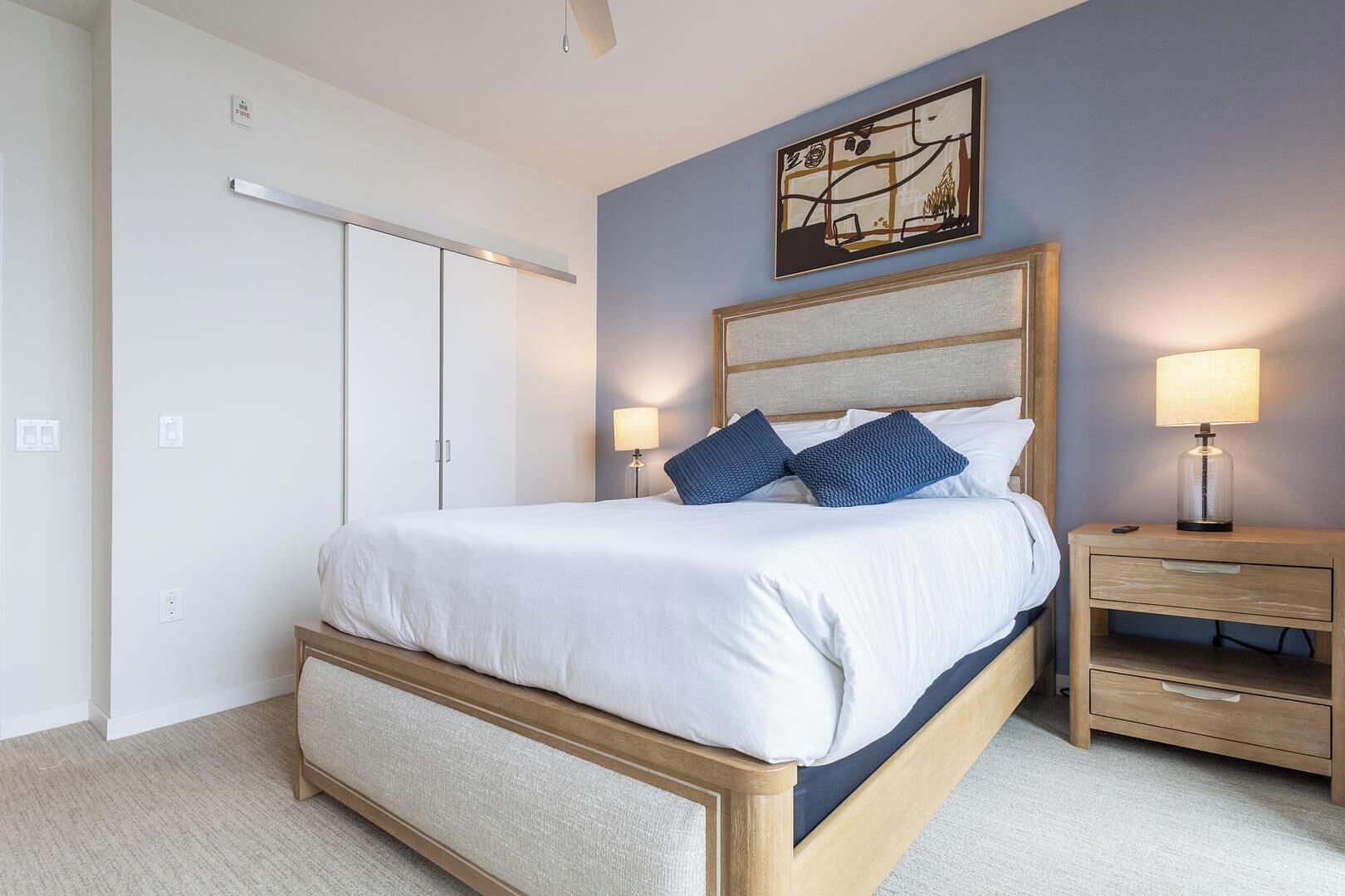 Un dormitorio ordenado con cama, mesitas de noche y armario.