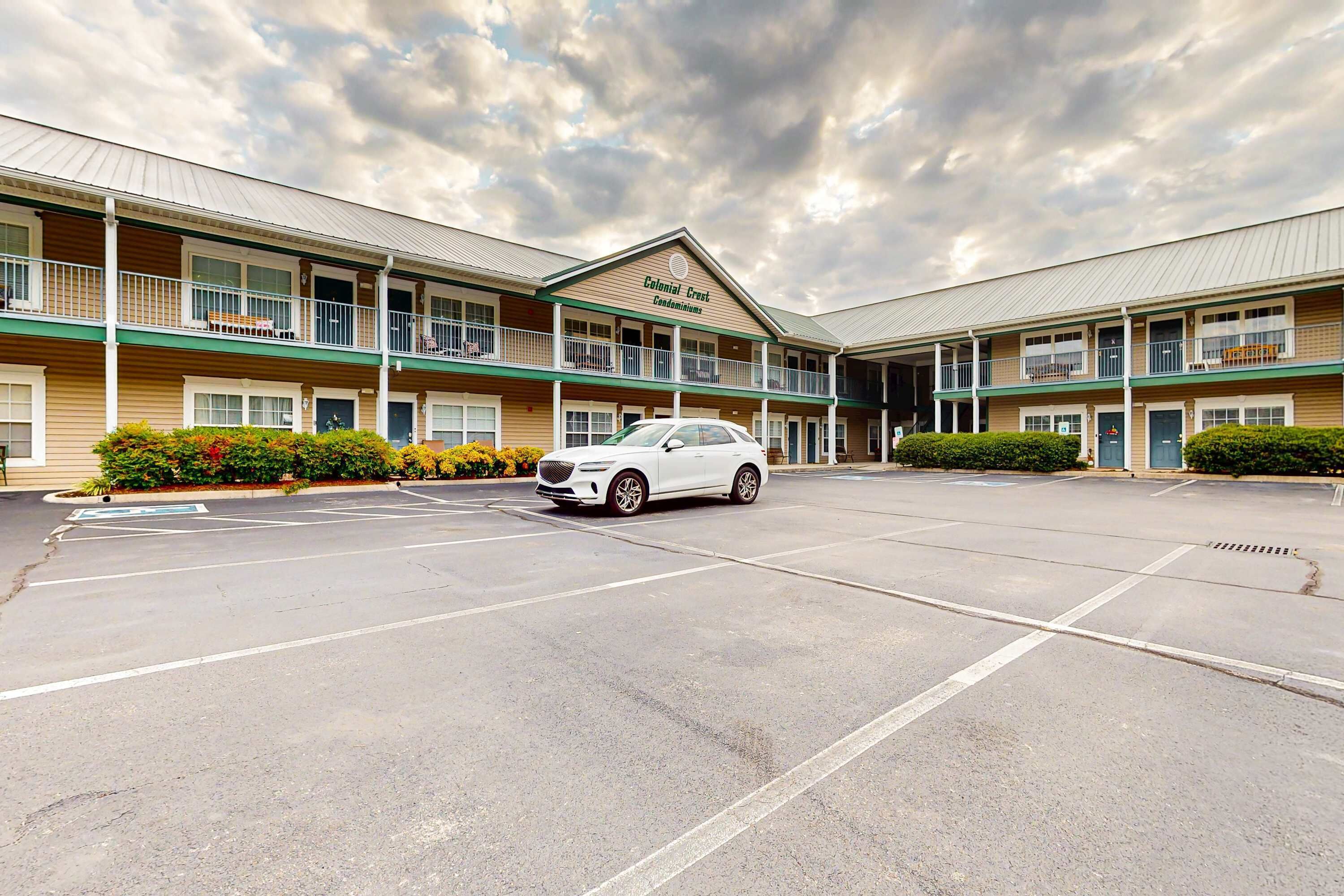 A Colonial Creek Condominium with a parking lot and a white car parked in front.