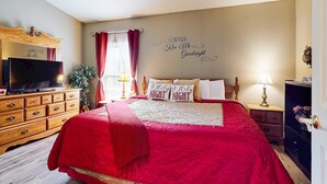Ein Schlafzimmer mit einem großen Bett, einer Holzkommode, einem Fernseher und einer Wand mit einer dekorativen Beschilderung.