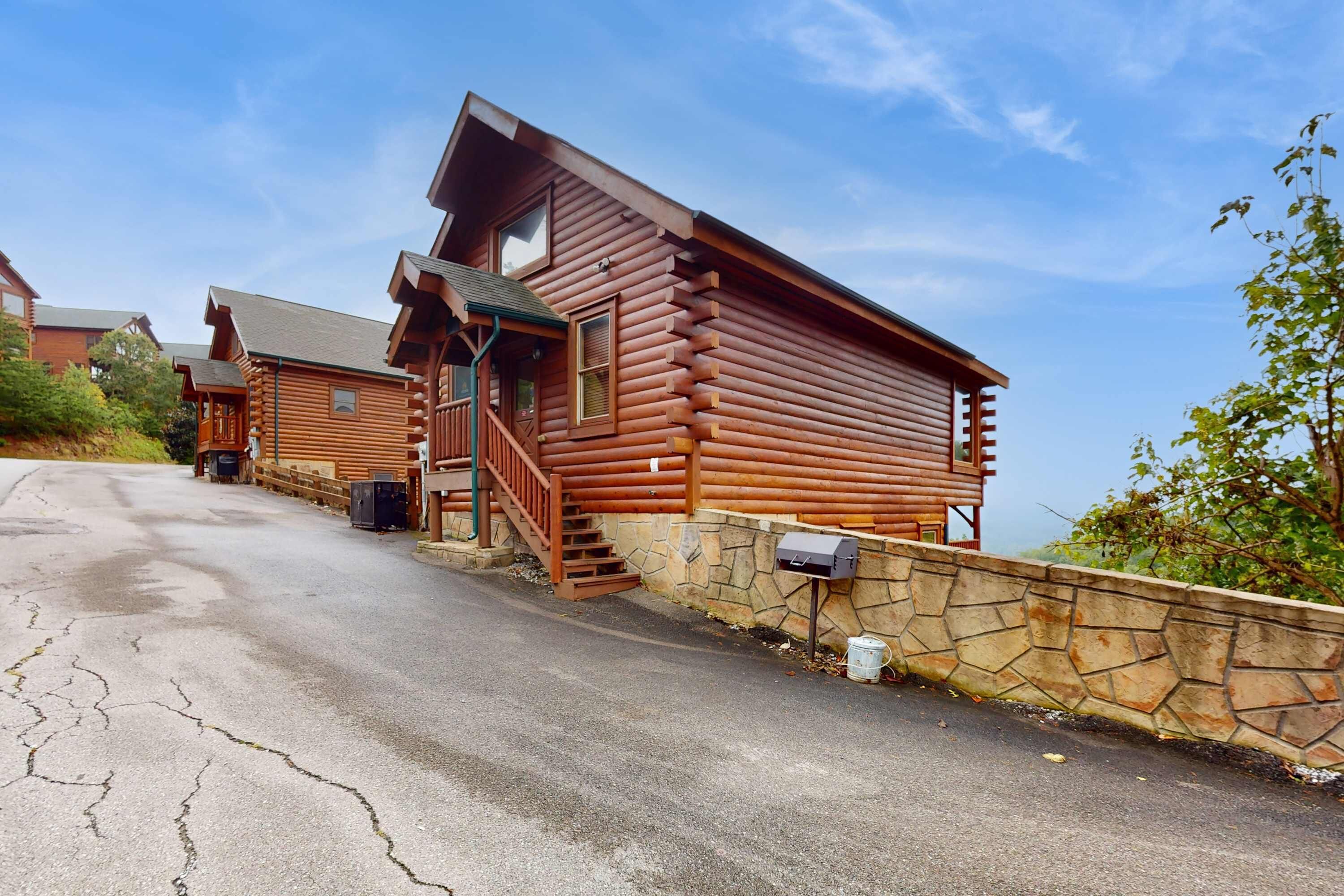 Une cabane en rondins, avec des fondations en pierre, une véranda en bois et un escalier menant à l’entrée.