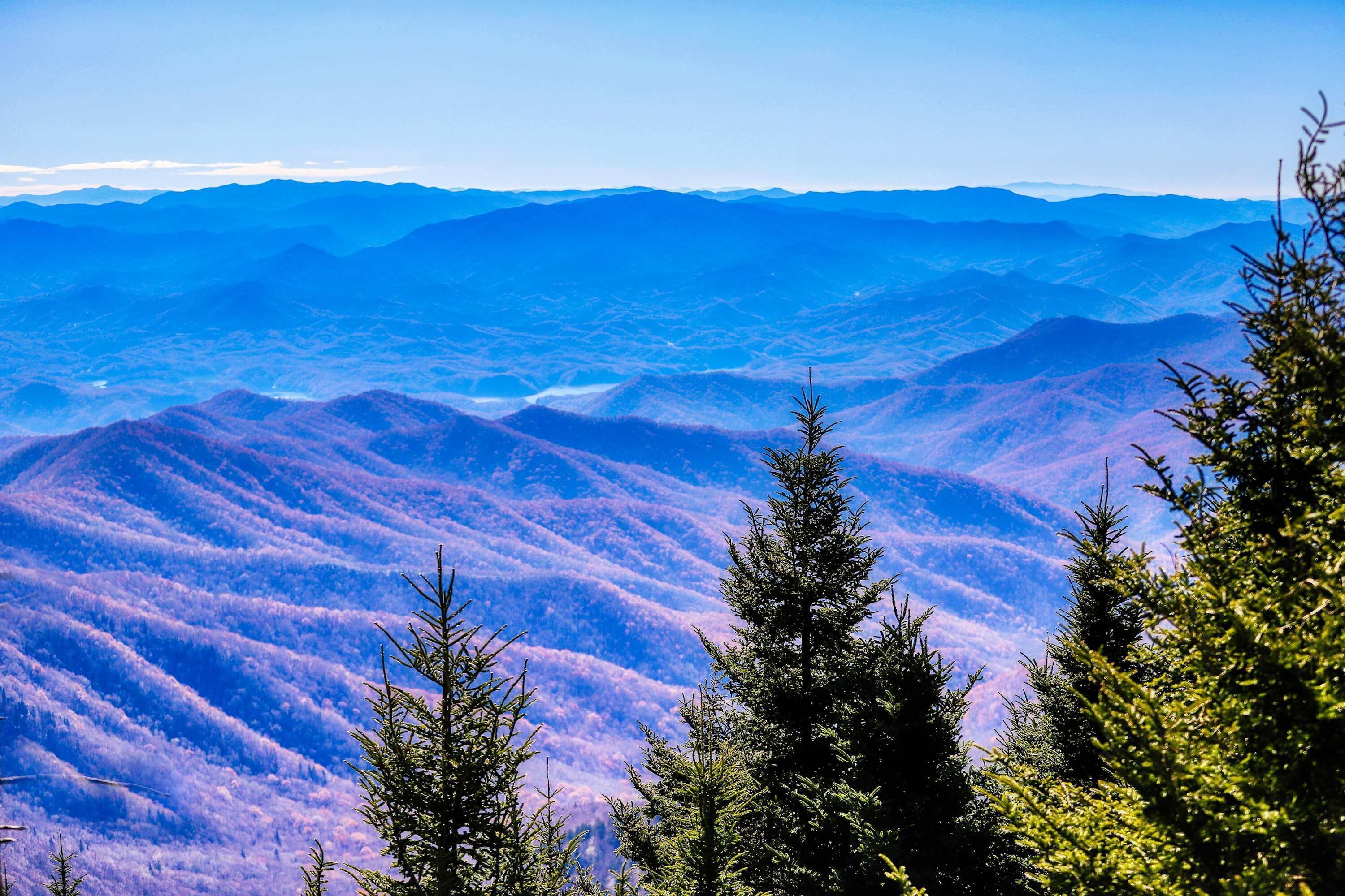 A mountainous landscape with dense forests and a clear sky.