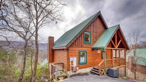 Eine Blockhütte mit grünem Dach, Holzfassade und einer Veranda.