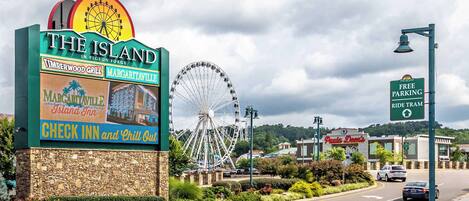 Señal de The Island en Pigeon Forge, con una noria de fondo.