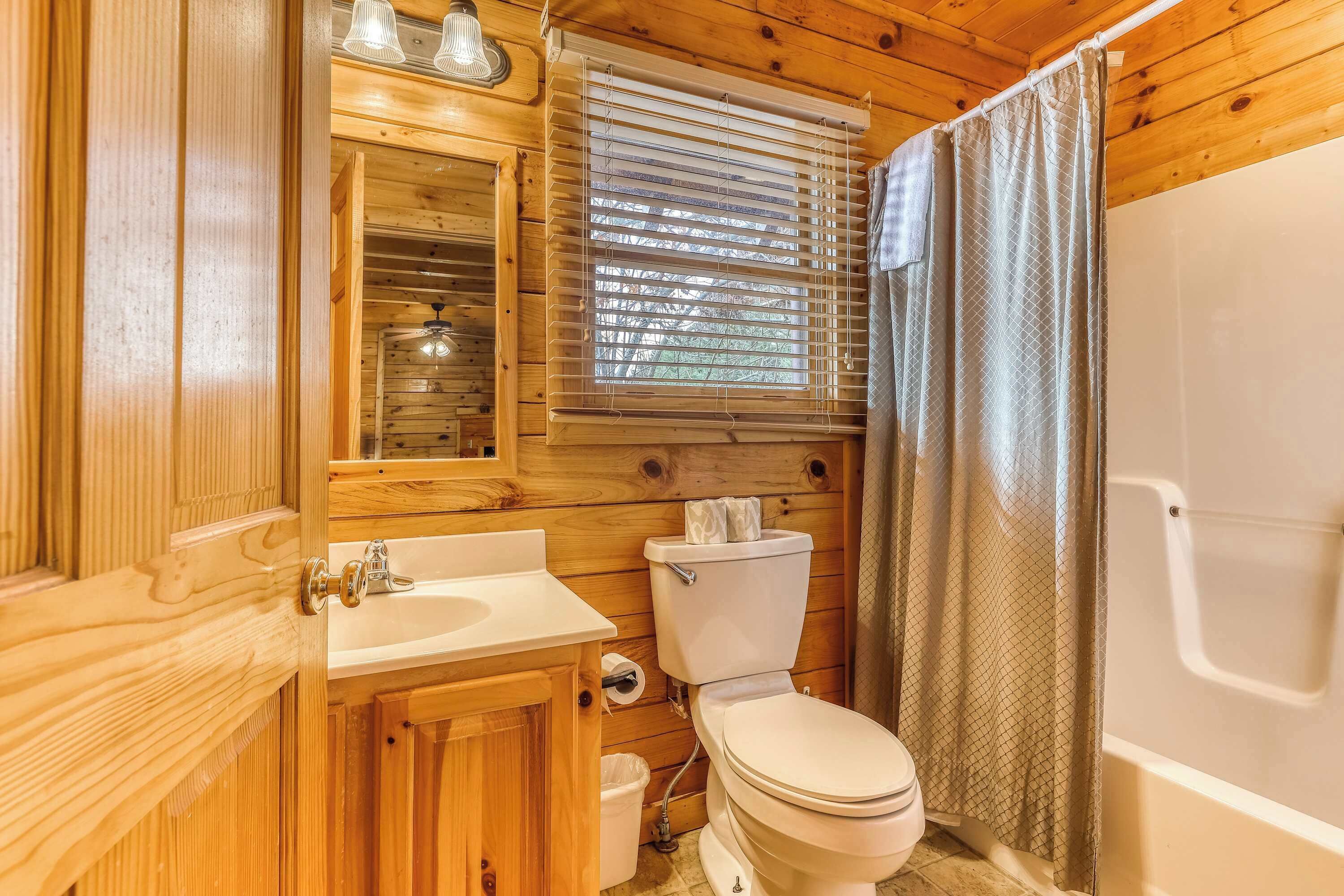 A wooden bathroom with a sink, toilet, and shower.