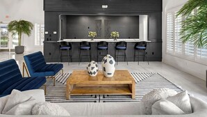 A modern living room with a sofa, a coffee table, and a kitchen area with bar stools. - Landing | Amazing 1BD, Clubhouse, Gym (Jacksonville)