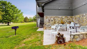 Un edificio con fachada de piedra y un patio techado con mobiliario exterior.