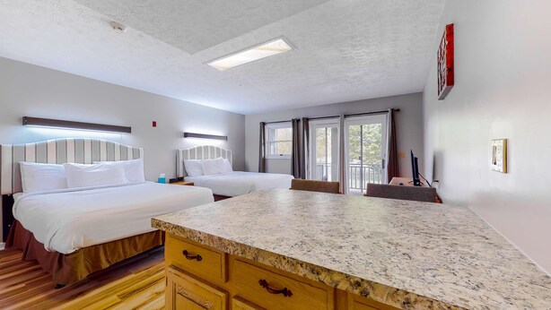 Habitación de hotel con dos camas, un armario de madera, una encimera de mármol e iluminación empotrada en el techo.