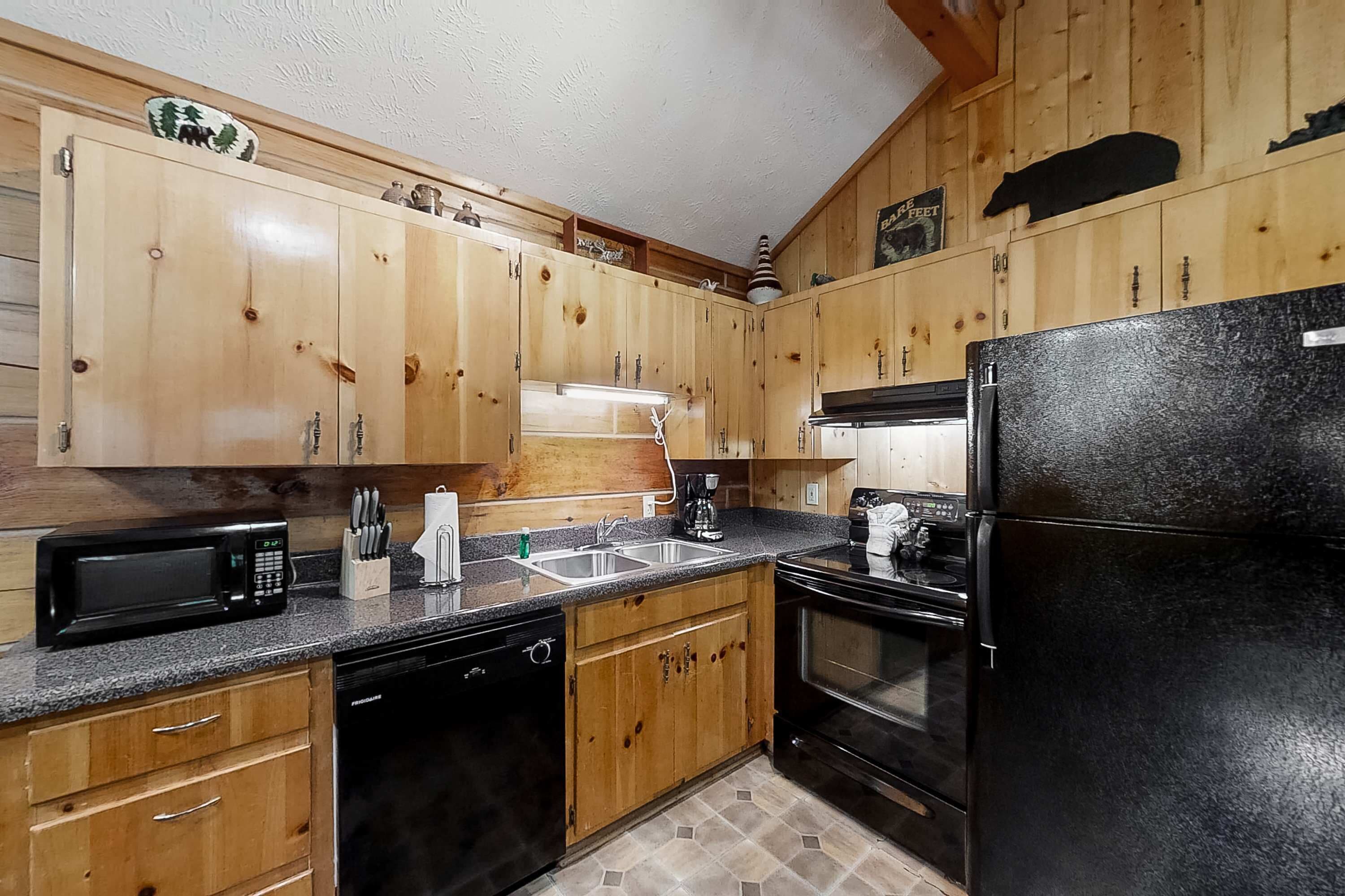 A kitchen with wooden cabinets, a black refrigerator, a microwave, and a dishwasher.