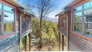 Una cabaña de madera con vista a un bosque y montañas.