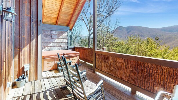 Una terraza de madera con una mesa y sillas, un lavamanos pequeño y vistas a las montañas.