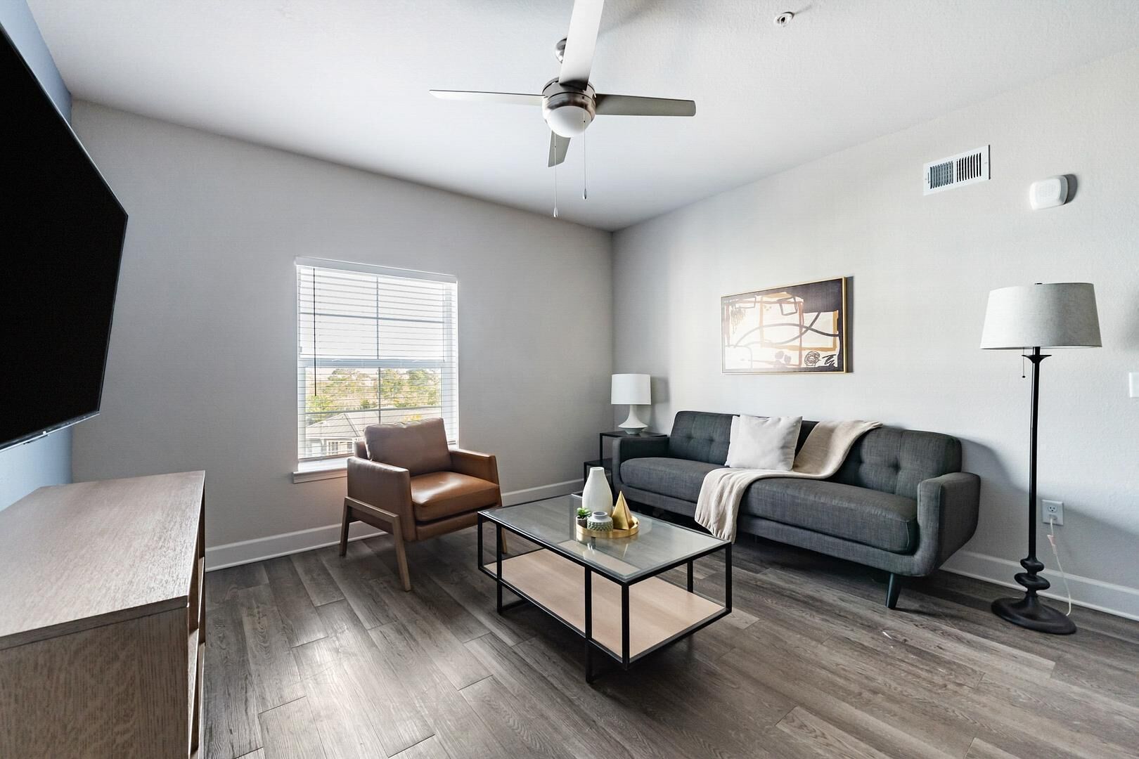 A modern living room with a sofa, armchair, coffee table, and floor lamp.