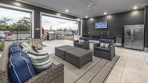 An outdoor patio with wicker furniture, a stone wall, and a view of the cityscape. - Landing | Spectacular 2BD, Yoga Studio, Gym (Palm Bay)