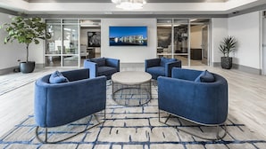 A modern lobby with a large seating area, a central coffee table, and a large window with a cityscape view. - Landing | Spectacular 2BD, Yoga Studio, Gym (Palm Bay)