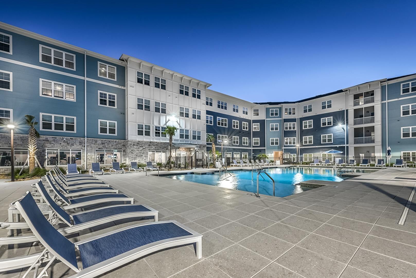 Ein Hotel mit Swimmingpool, Liegestühlen und einer Steinfassade.