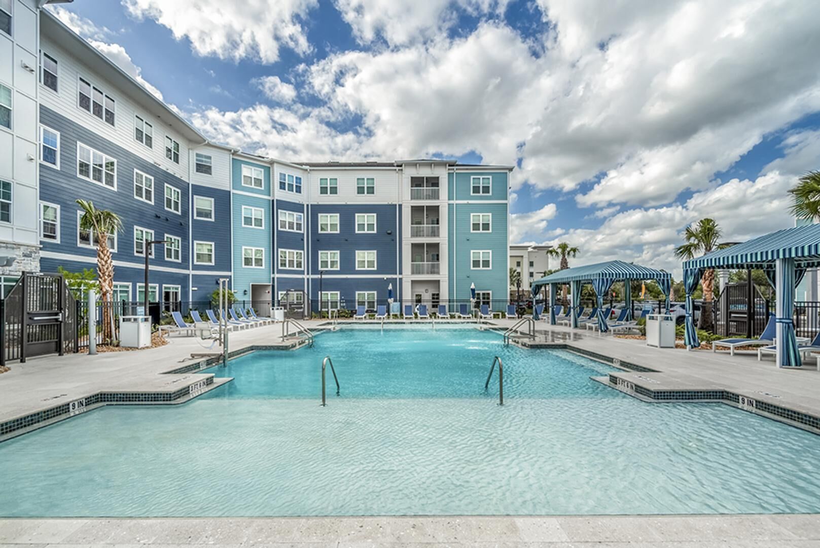 Ein Hotel mit großem Pool, mehreren Balkonen und einer überdachten Sitzgelegenheit.