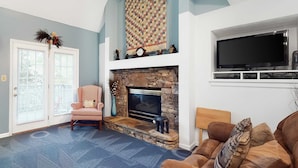 A living room with a stone fireplace, a television mounted above it, and a large window. - 4 Mi. to Parkway・Near Dollywood Stay・Hot Tub・Pool (Pigeon Forge)