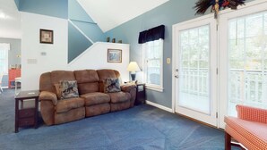 A living room with a brown sofa, a small table, and a lamp. There is a staircase leading to another level, and a door with a window. - 4 Mi. to Parkway・Near Dollywood Stay・Hot Tub・Pool (Pigeon Forge)