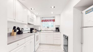 A modern kitchen with white cabinets, a stainless steel refrigerator, and a window with a red valance. - 4 Mi. to Parkway・Near Dollywood Stay・Hot Tub・Pool (Pigeon Forge)