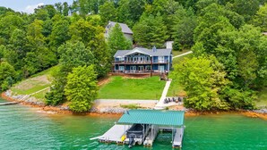 A lakeside house with a dock and a covered boat launch area.