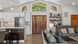 A modern kitchen with a central island, stainless steel appliances, and a dining area with a wooden table and chairs.