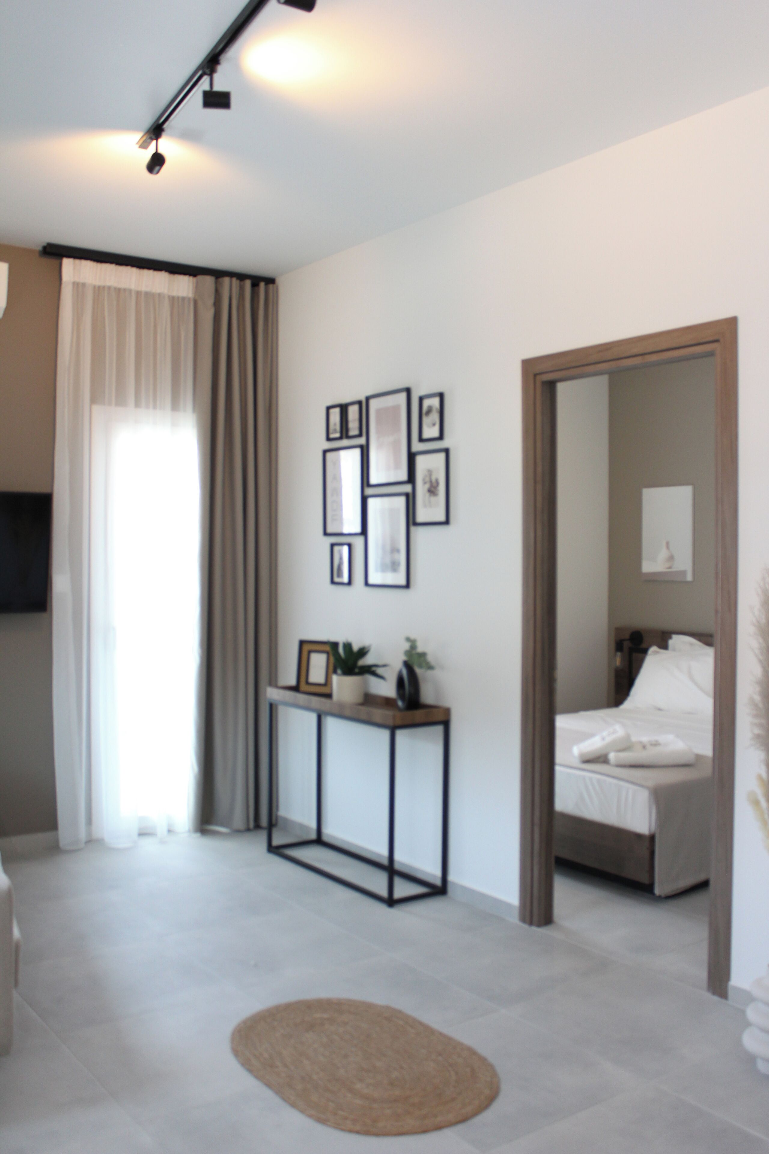 Une chambre d’hôtel moderne, équipée d’un lit, d’une table de chevet agrémentée d’une plante, d’un miroir et de tableaux encadrés accrochés au mur.