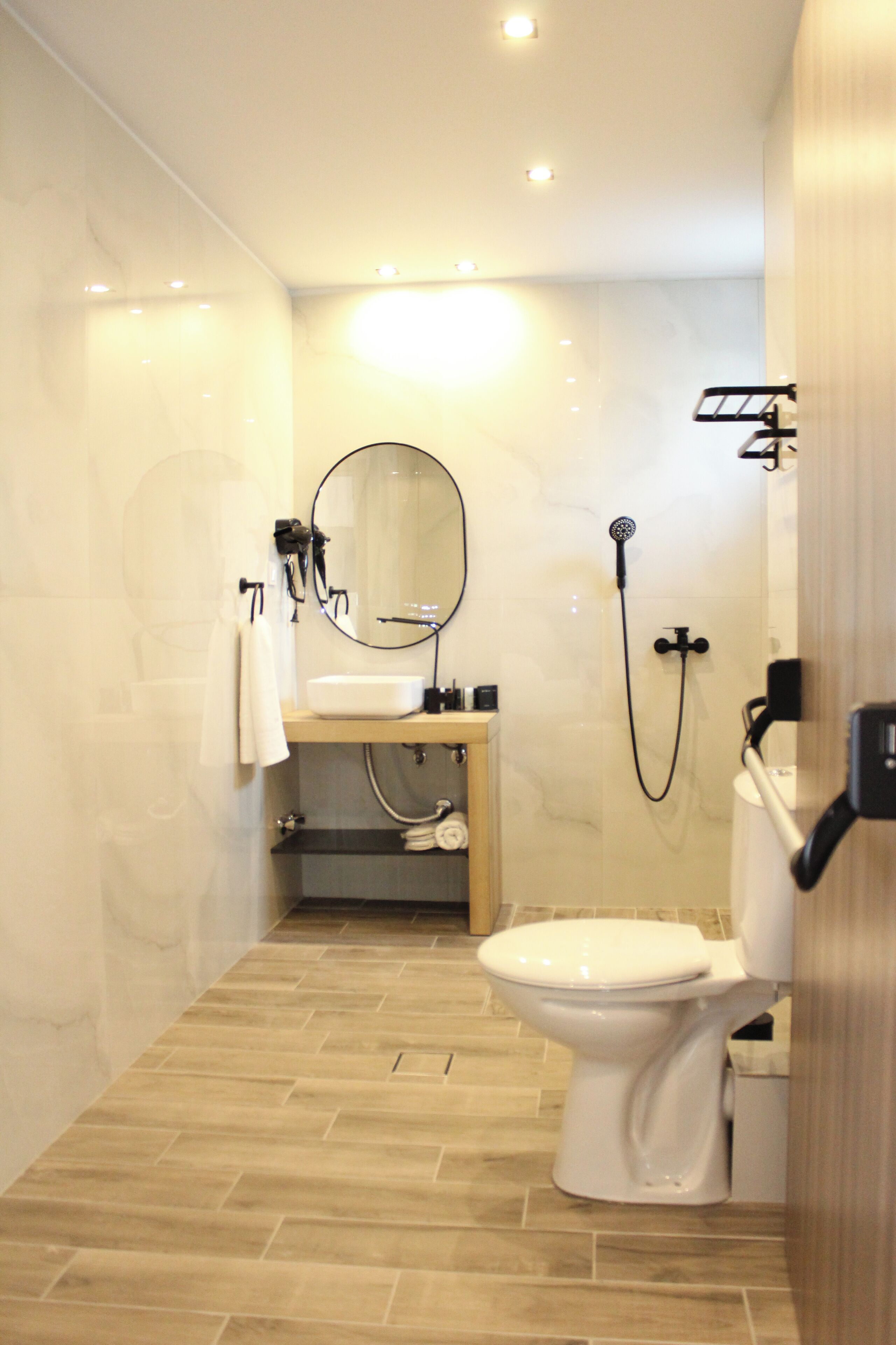Un baño moderno con inodoro, lavabo, espejo y ducha.
