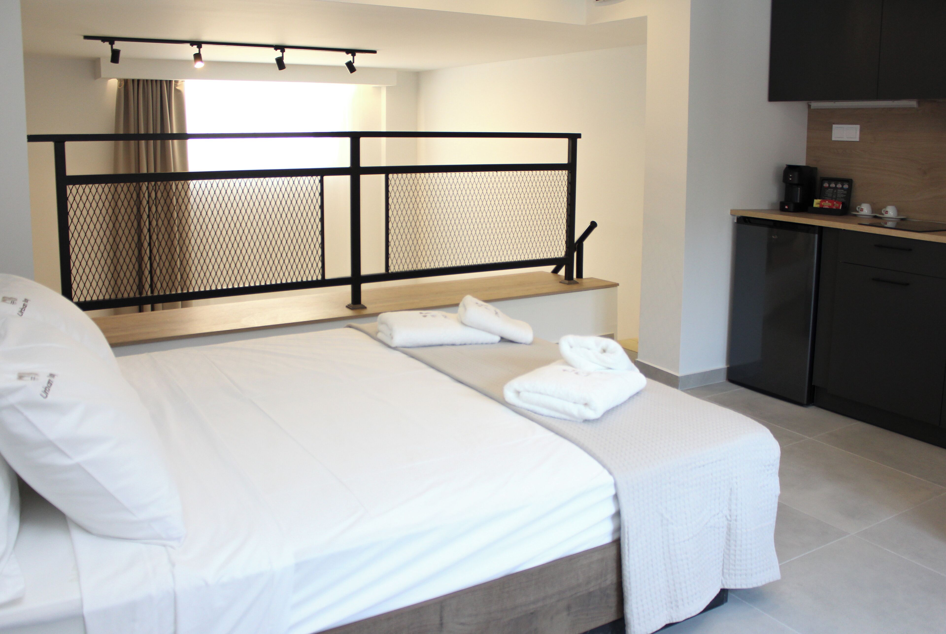 Una habitación de hotel con cama, una kitchenette pequeña y una ventana con cortinas.