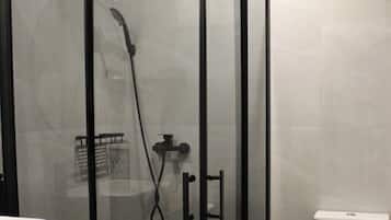 A modern bathroom with a glass-enclosed shower, a white toilet, and a wooden vanity with a sink.