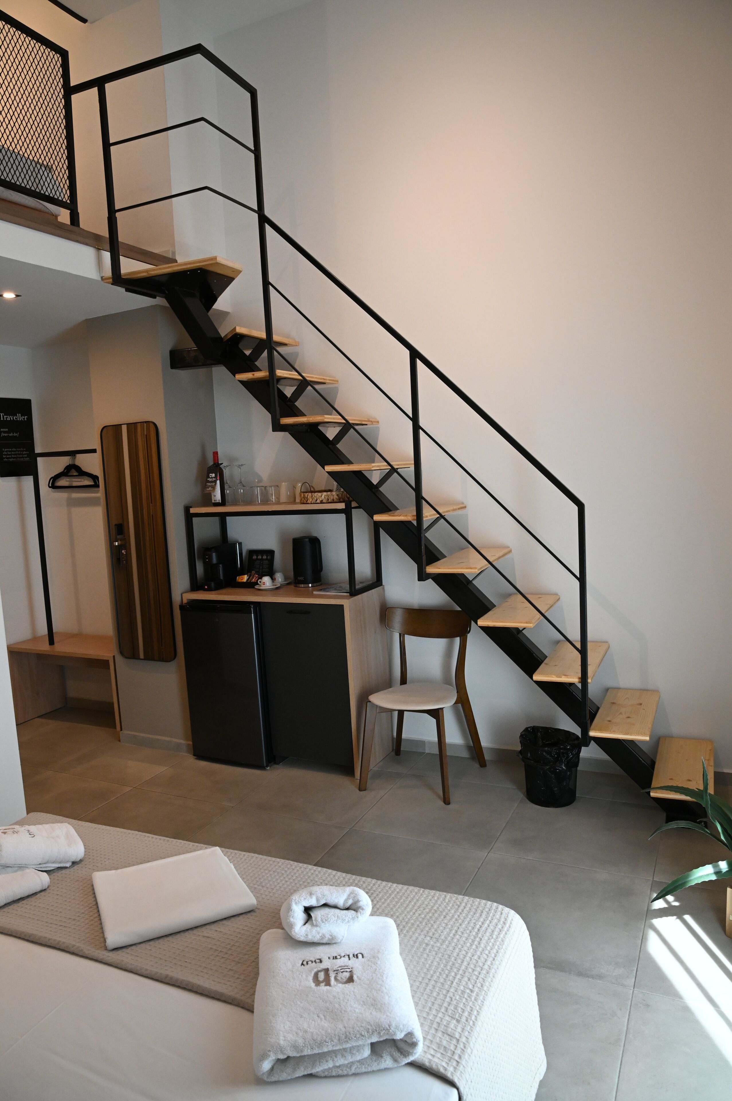 Une chambre d’hôtel moderne équipée d’un escalier, d’une petite kitchenette, d’un lit et d’un coin salon.