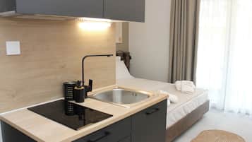 Een compacte kitchenette met een ingebouwd fornuis, een spoelbak en een klein aanrecht.