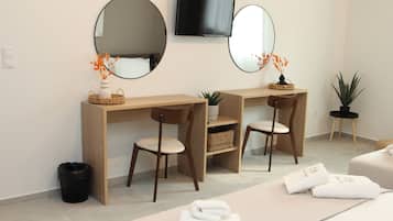 Een moderne kamer met een houten bureau, twee stoelen, een televisie en een massagetafel met handdoeken.