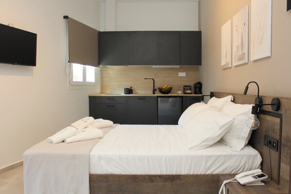 A modern hotel room with a bed, bedside table, and a small kitchenette. - UrbanBay Hotel & Spa (Kavala)
