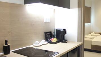 A modern kitchen with a built-in induction cooktop, a coffee maker, and a small breakfast bar area.