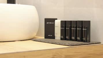 Un tocador de baño con un lavabo blanco, una caja de tocador negra y cuatro botellas negras etiquetadas 'Artisti Italiani'.