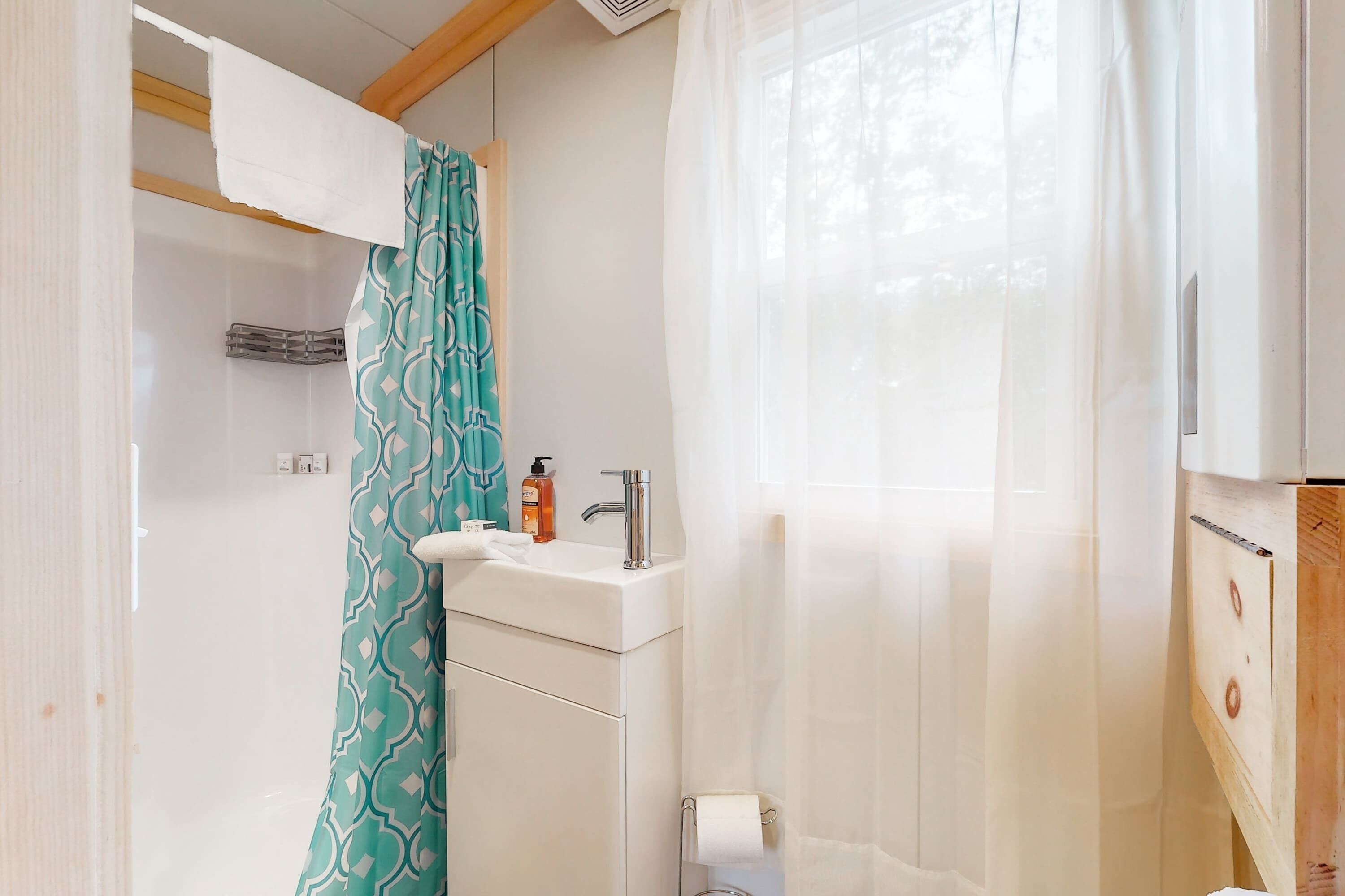 Un baño con lavamanos, espejo y perchero para toallas.