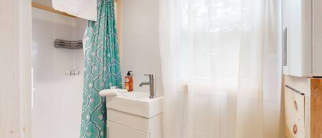 Un baño con lavamanos, espejo y perchero para toallas.
