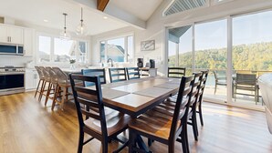 Une cuisine moderne avec des meubles blancs, un grand îlot central et un coin repas doté de chaises en bois.