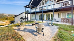 Une maison moderne à deux étages dotée d’un patio aménagé avec des meubles d’extérieur et un foyer.