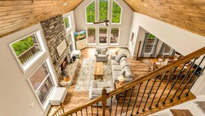 Un loft amplio con techo alto, ventanas grandes, chimenea de piedra y una escalera de madera.