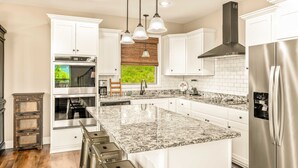 Una cocina moderna con armarios blancos, electrodomésticos de acero inoxidable, encimera de granito y una isla grande con taburetes de bar.