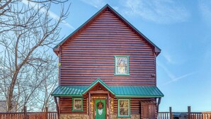 A large log cabin with a green door and a stone foundation. - Homey Cabin, Sleeps 8, Hot Tub, Theater, Games, Views (Pigeon Forge)