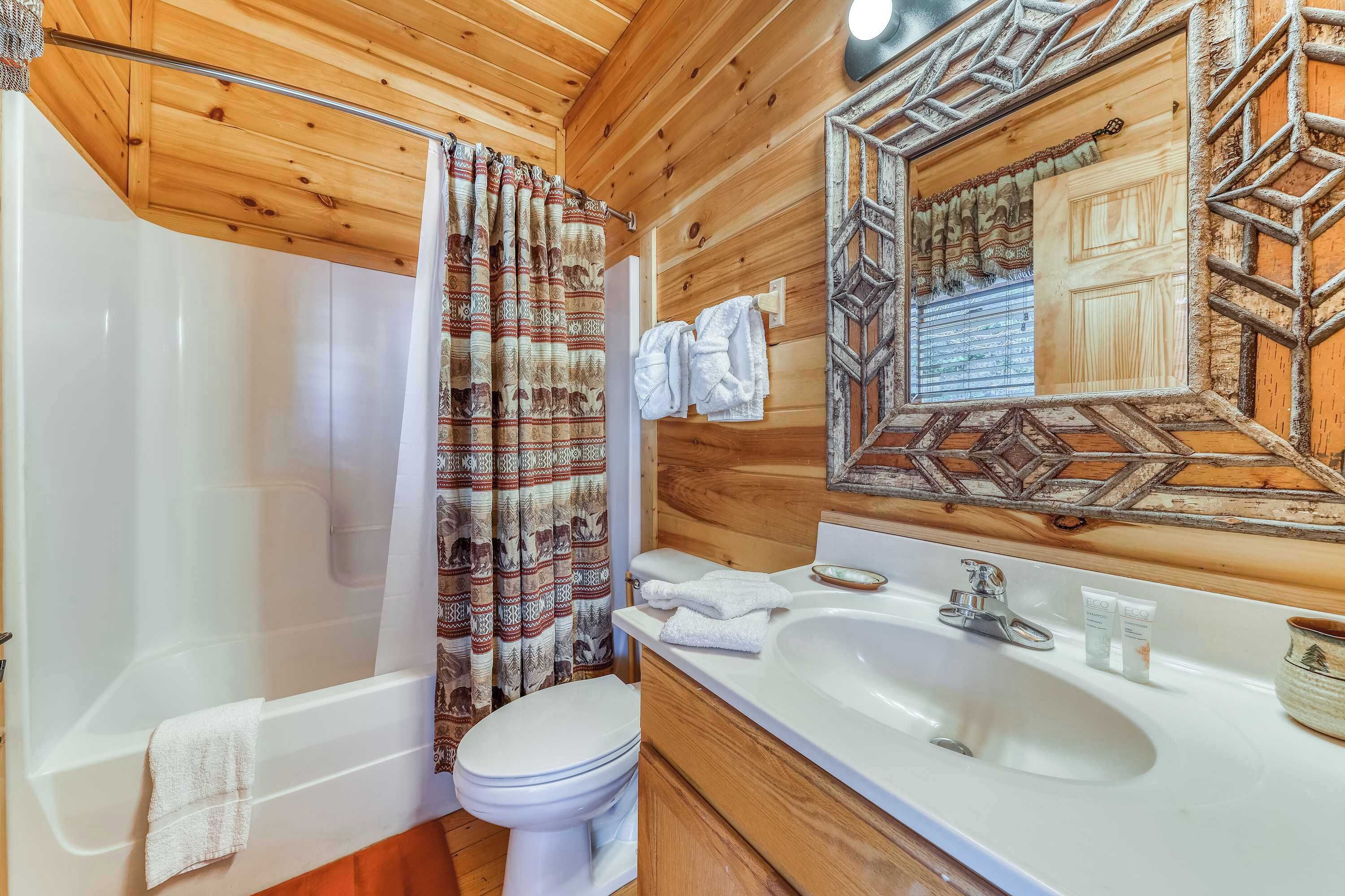 A wooden-paneled bathroom with a bathtub, toilet, and sink.