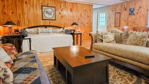 Een gezellige kamer met een bed, een sofa, een salontafel en een houten wand.