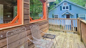 Een houten terras met twee metalen stoelen en een kleine tafel.