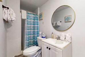 Een badkamer met een toilet, een wastafel met spiegel en een douchegordijn.