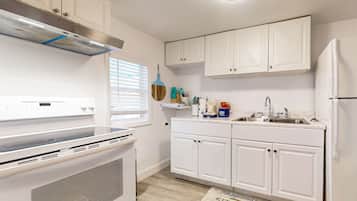 A modern kitchen with white cabinets, a stainless steel range hood, a built-in oven, a sink, and a refrigerator.