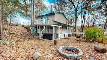 A cabin with a porch, a fire pit, and a deck.