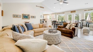 A spacious living room with a beige sectional sofa, ottoman, and a ceiling fan. - Spacious Norris Lakefront Retreat・Firepit・Hot Tub (Maynardville)
